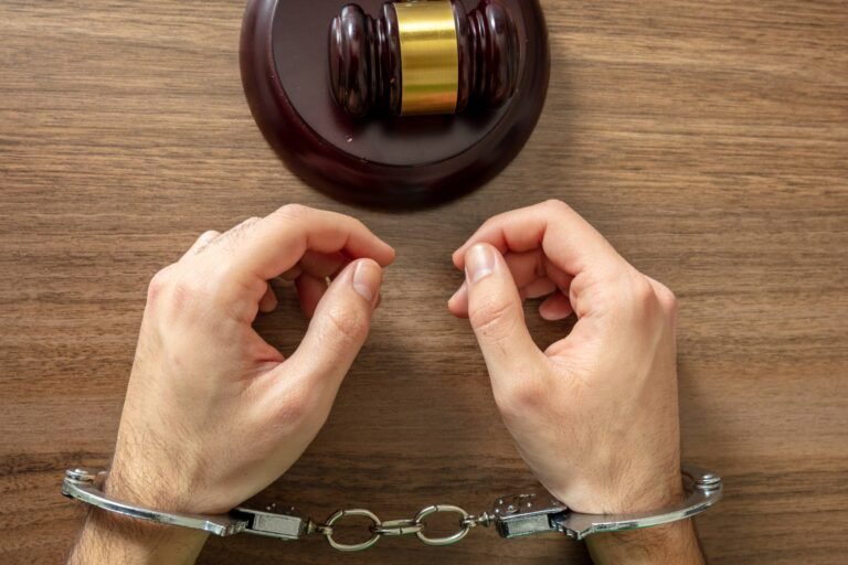 Handcuffed Convict. Court sentence Prison. Handcuff locked and judge gavel on table, top view..